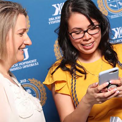 student with phone in hand talking with alumni